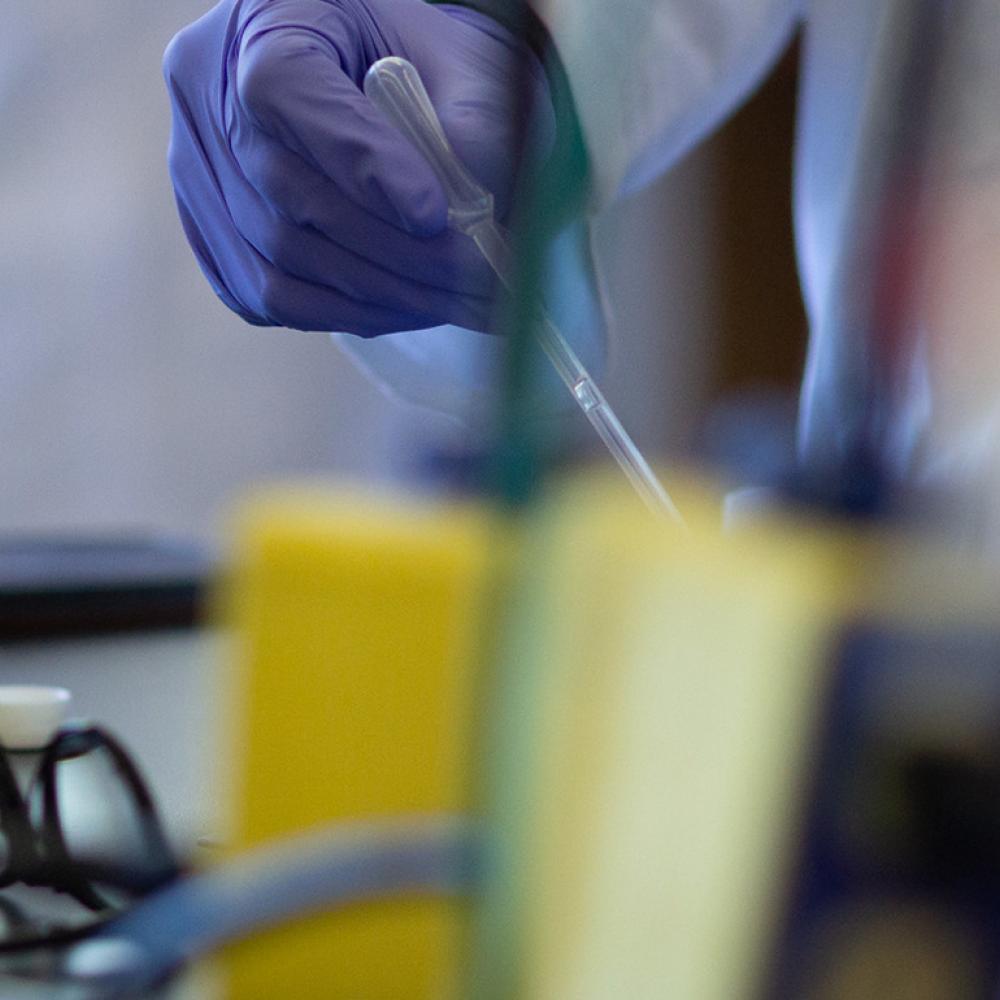 Vial of liquid sits next to pair of glasses on a lab table 